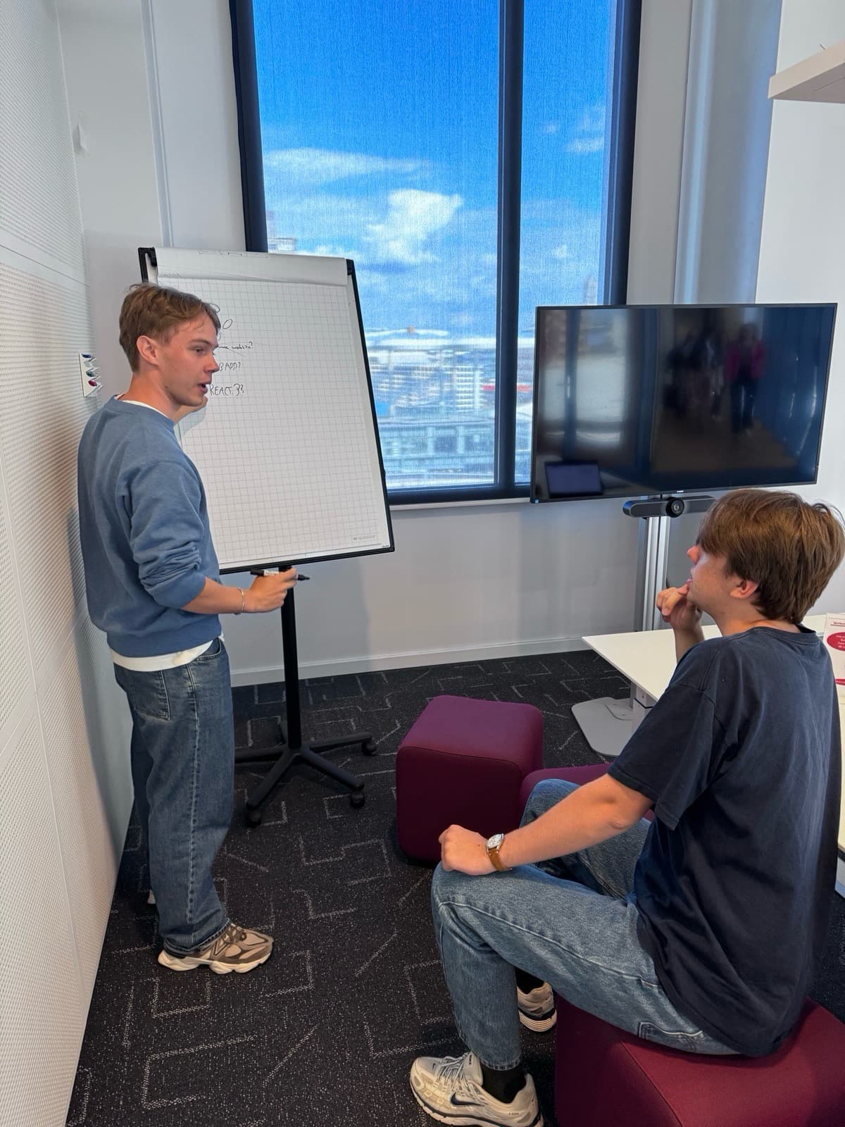 Timo legt iets uit bij een flip-over, een collega kijkt mee